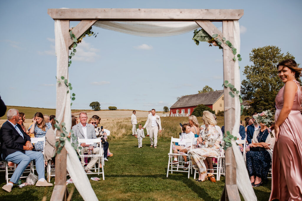 Bröllopsfotograf Skåne - Vigselplats där alla gäster sitter, och brudgum och son är påväg fram.
