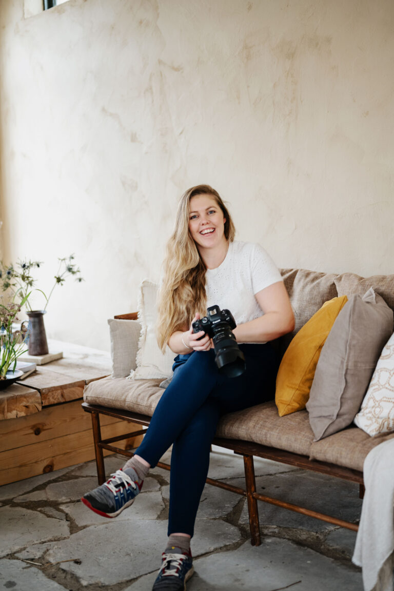 Bröllopsfotograf Skåne - en kvinna som sitter på en bänk med sin kamera i handen och ler stort in i kameran